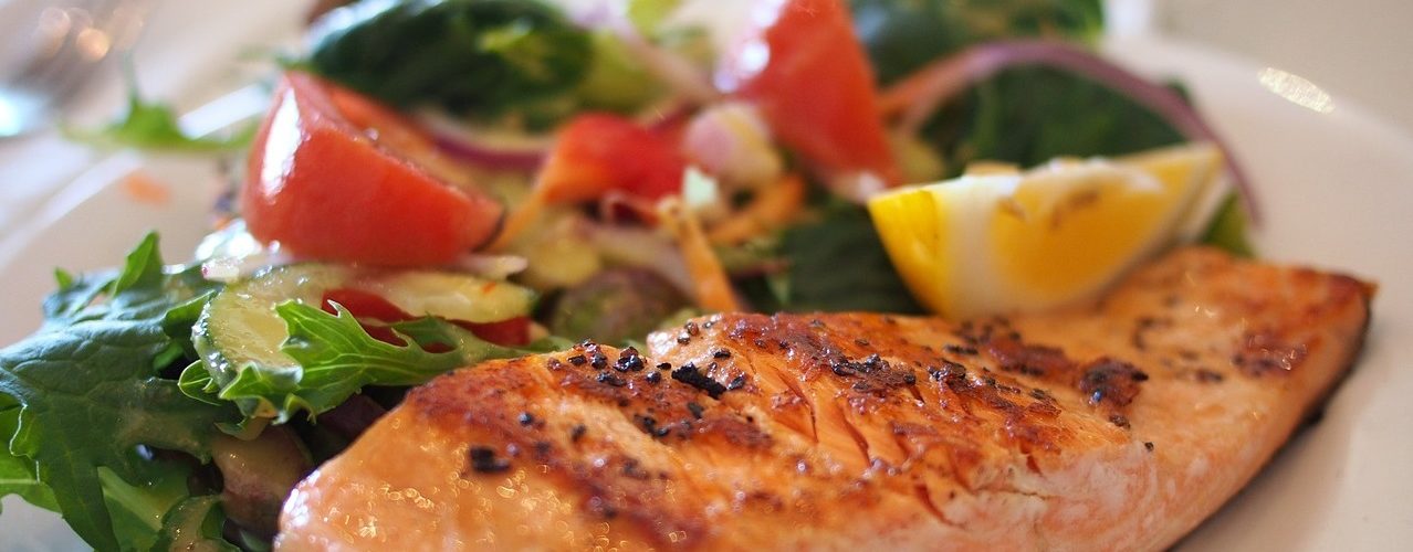 Tallrik med stekt lax och grönsaker.