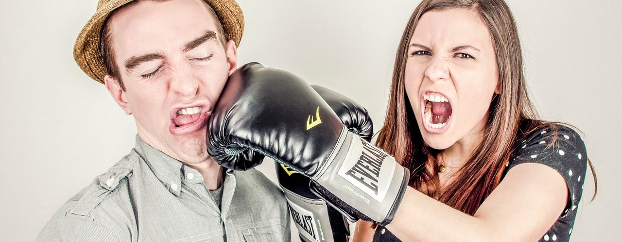 En kvinna med boxhandskar som slår en man i ansiktet.