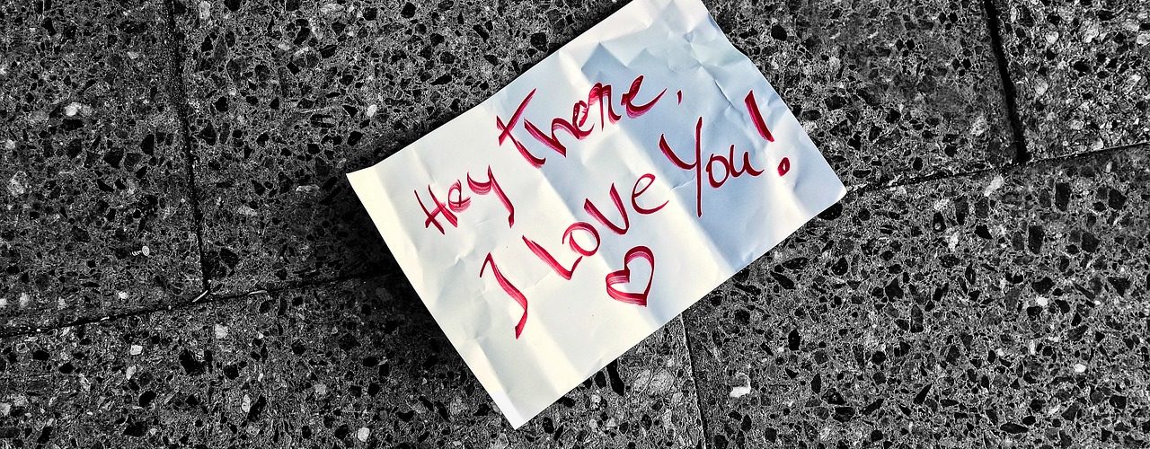 Ett papper som ligger på grå plattor. Texten är skriven i rött och lyder: Hey there I love you!