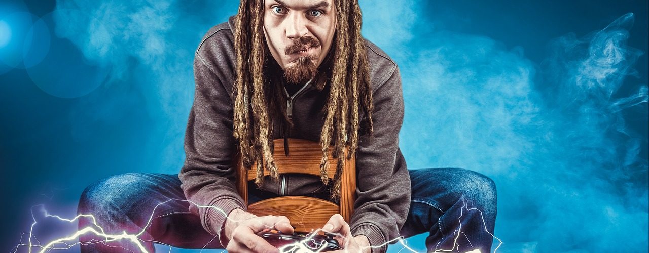 En man med dreadlocks sitter och spelar spel med djup koncentration.