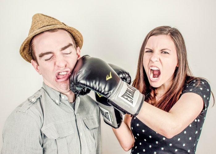 En kvinna med boxhandskar som slår en man i ansiktet.