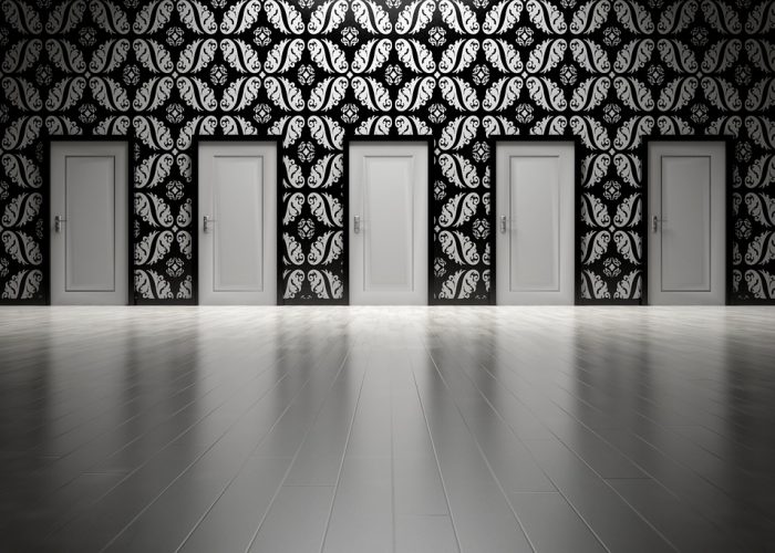 Många vita dörrar mot en svartvit-mönstrad tapet.