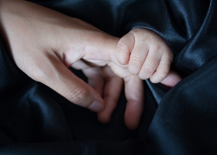 En liten bebishand håller runt en vuxens pekfinger.